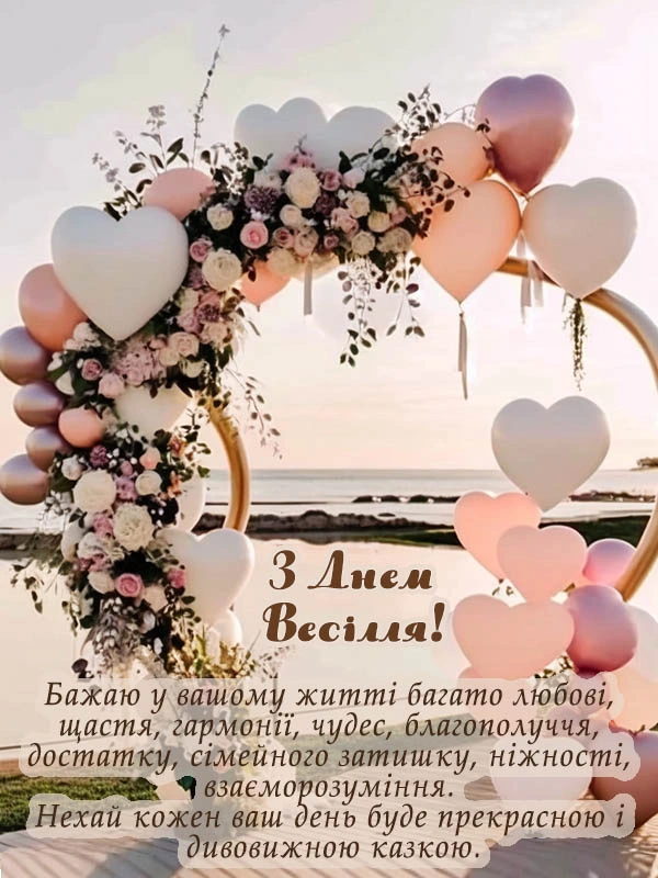 Весільна арка з балонами-сердечками та квітами на фоні заходу сонця.