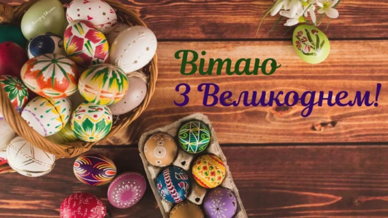 Корзина з розписаних пасхальних яєць на дерев'яному столі.