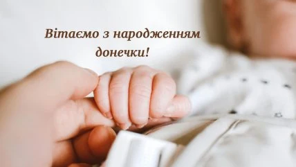 Доросла рука тримає маленьку ручку новонародженої доньки.