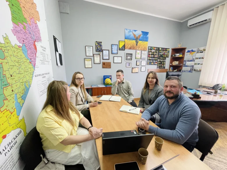 Група людей обговорює документи за столом у офісі.